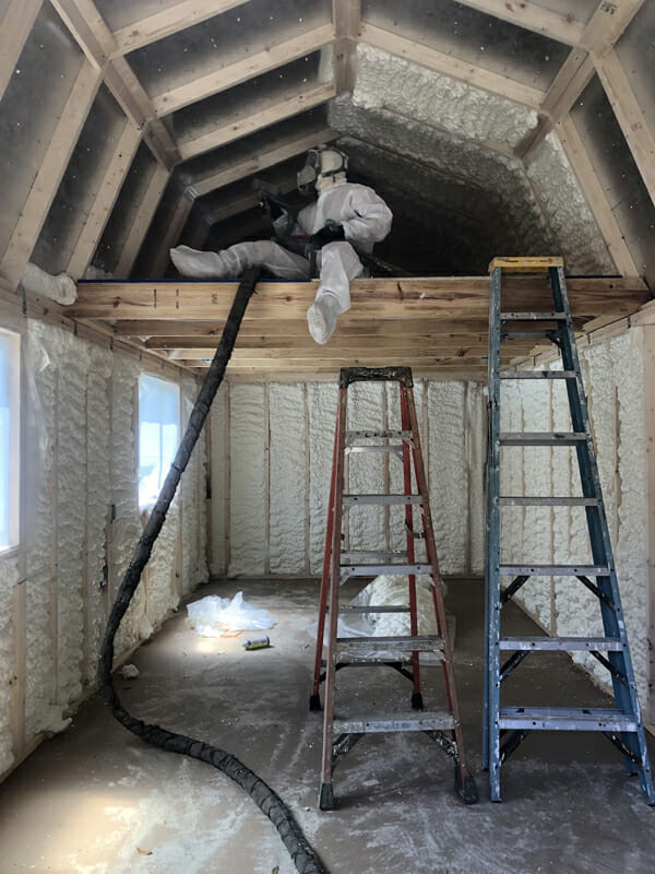 Worker in loft area of building spraying foam insulation